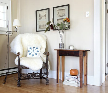 Chair with sheepskin in living room next to coffee table.